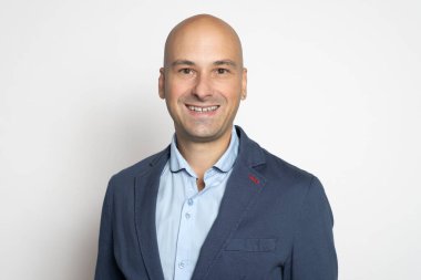 Ceketli yakışıklı kel adam stüdyo duvarında gülümsüyor..