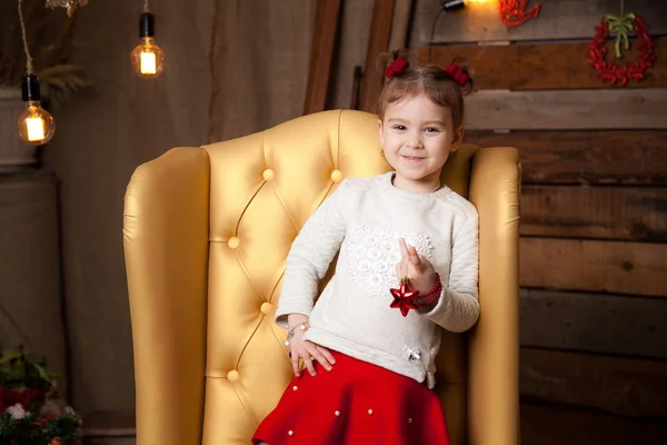 Uma menina em uma bela cadeira amarela. Fundo de Ano Novo — Fotografia de Stock