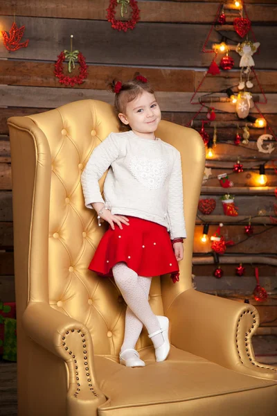 Een klein meisje in een mooie gele stoel. New Year's achtergrond — Stockfoto