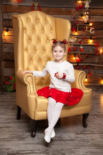 Uma menina em uma bela cadeira amarela. Fundo de Ano Novo — Fotografia de Stock