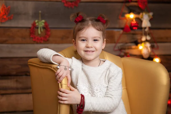 Uma menina em uma bela cadeira amarela. Fundo de Ano Novo — Fotografia de Stock