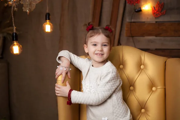 Uma menina em uma bela cadeira amarela. Fundo de Ano Novo — Fotografia de Stock