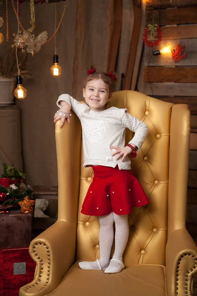 Uma menina em uma bela cadeira amarela. Fundo de Ano Novo — Fotografia de Stock