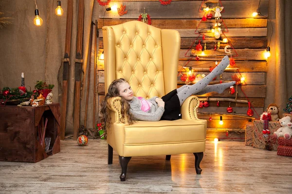 Маленькая девочка в красивом желтом кресле. Новогодний фон — стоковое фото