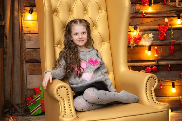 Een klein meisje in een mooie gele stoel. New Year's achtergrond — Stockfoto