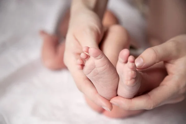 Benen van de baby in moeder's handen — Stockfoto