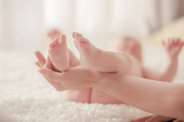 Las piernas del bebé en las manos de la madre — Foto de Stock