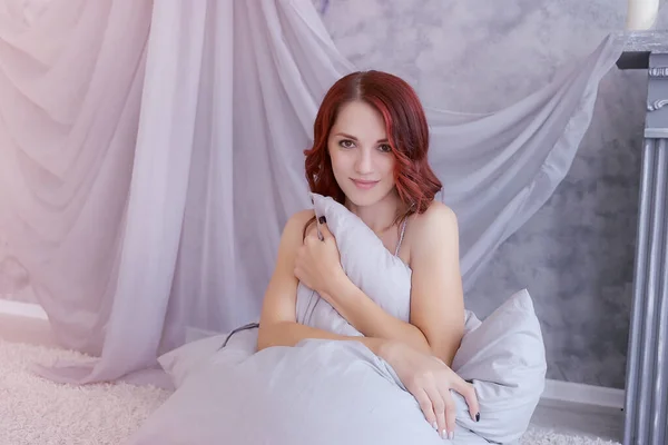 Young happy girl hugs a pillow while sitting on the floor — 스톡 사진