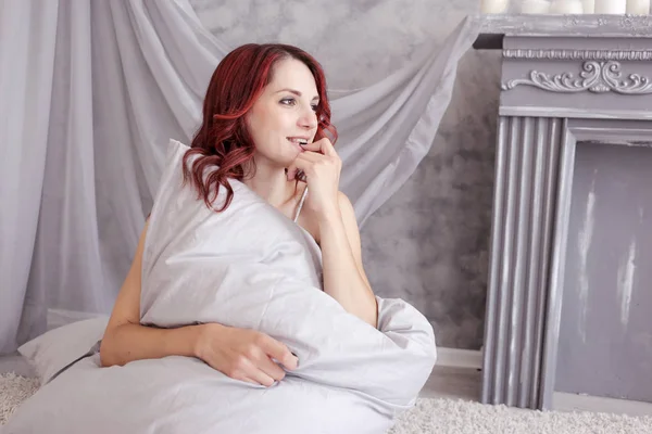 Young happy girl hugs a pillow while sitting on the floor — 스톡 사진