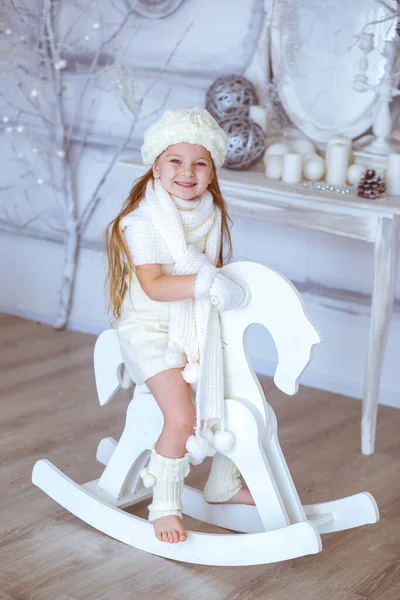 Menina em um cavalo de madeira em um fundo de Natal — Fotografia de Stock