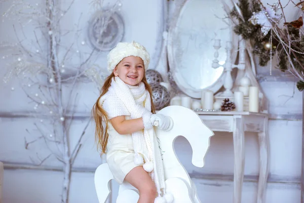 Menina em um cavalo de madeira em um fundo de Natal — Fotografia de Stock