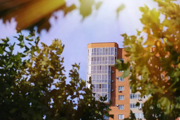 Yeni konut binası, ağaç yaprakları arasında pencereler. — Stok fotoğraf