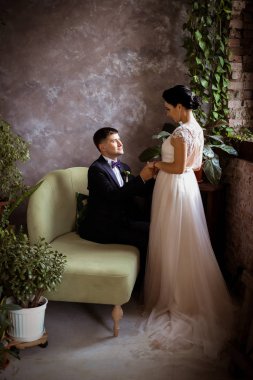 Şık bir elbise içinde gelin ve arka planda bir takım elbise içinde damat