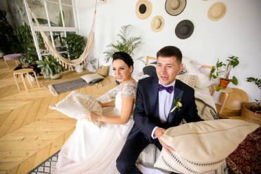 Mutlu yeni evliler oynuyorlar ve yastıklarla oynuyorlar.