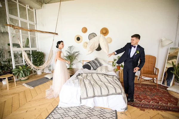 Feliz recién casados juegan y tontean con almohadas — Foto de Stock