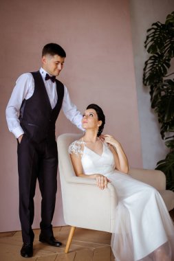 Pembe bir sandalyede oturan zarif elbiseli güzel bir gelin. 