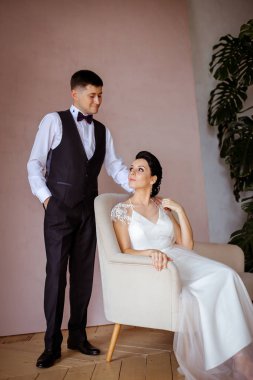 Pembe bir sandalyede oturan zarif elbiseli güzel bir gelin. 