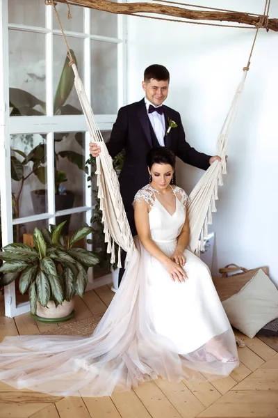 Noiva bonita em um vestido elegante senta-se em uma rede macrame um — Fotografia de Stock