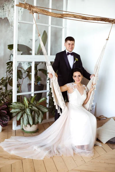 Vacker brud i en elegant klänning sitter i en macrame hängmatta en — Stockfoto