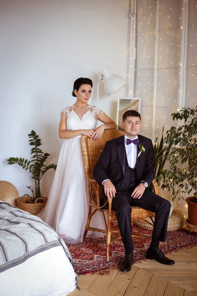 Hermosa novia en un vestido elegante y el novio en un traje en una tetona — Foto de Stock