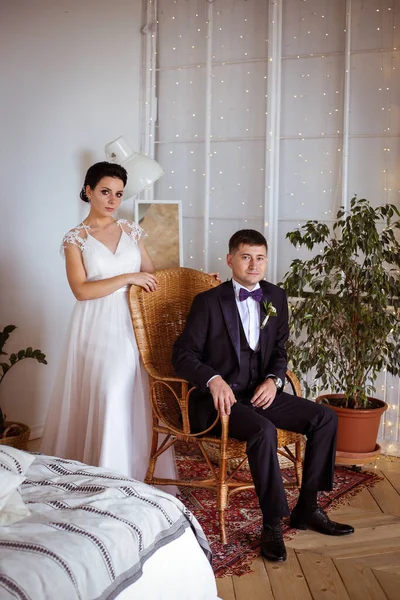 Hermosa novia en un vestido elegante y el novio en un traje en una tetona — Foto de Stock