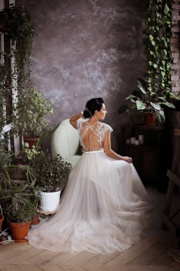 Zarif bir elbise içindeki güzel gelin koltukta arkasına yaslanır. 