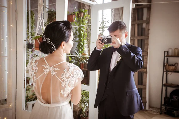 Ένας γαμπρός με κοστούμι φωτογραφίζει μια όμορφη νύφη με ένα κομψό dr — Φωτογραφία Αρχείου