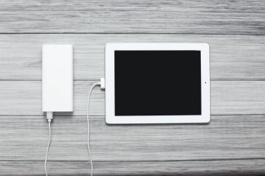 Bir tablet ve bir güç bankası tahtanın arka planında para alıyor.