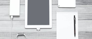 Tablet, boş defter, telefon ve şarj aleti.