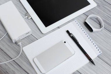 Tablet, boş defter, telefon ve şarj aleti.
