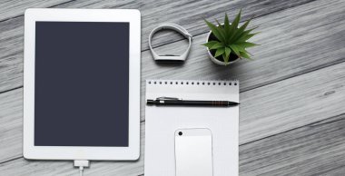 Tablet, boş defter, telefon ve şarj aleti.