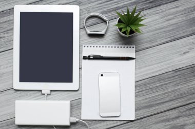 Tablet, boş defter, telefon ve şarj aleti.