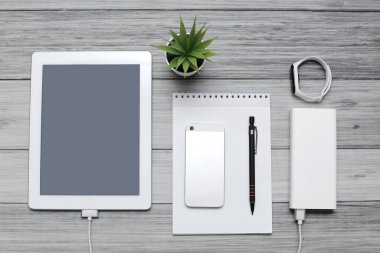 Tablet, boş defter, telefon ve şarj aleti.