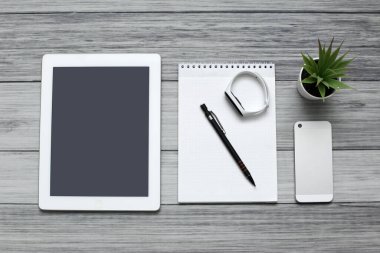 Tablet, boş defter, telefon ve şarj aleti.