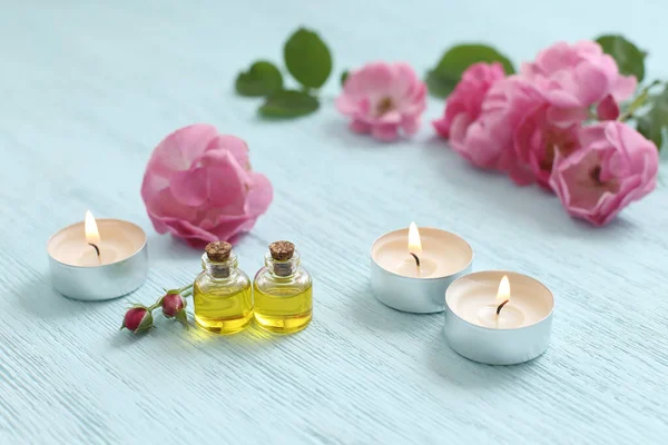 Rosehip cosmetic oil in mini bottles and pink rosehip flowers. Spa treatments for relaxation.