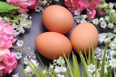 Siyah desenli arka planda bahar çiçekleri arasında paskalya yumurtaları.