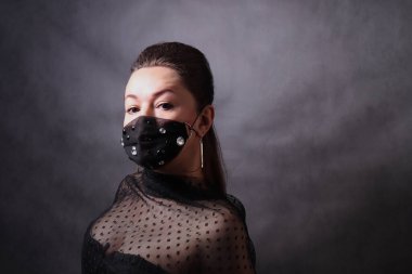 Woman in a black protective mask with rhinestones. Pandemic virus COVID-19 clipart
