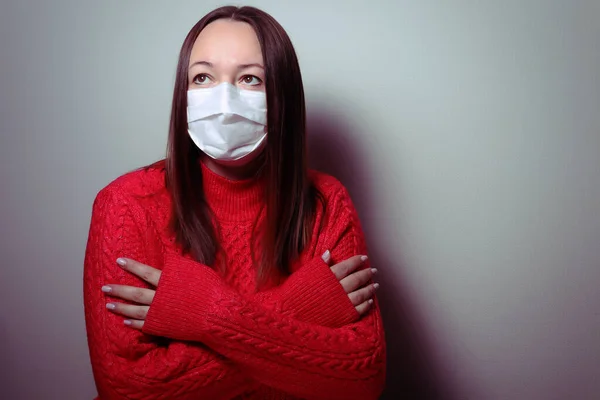 Masked woman in a red sweater. Quarantine at home during a pandemic.Pandemic virus COVID-19