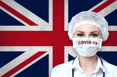 Büyük Britanya bayrağının bulanık arka planında COVID-19 yazısıyla tıbbi maskeli kadın doktor. Salgın virüs COVID-19. Sağlık ve Tıp Konsepti. 