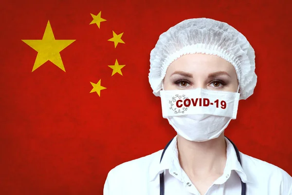 戴口罩的女医生在国旗模糊的背景上刻着Covid 19字样 大流行性病毒Covid 保健和医疗概念 — 图库照片