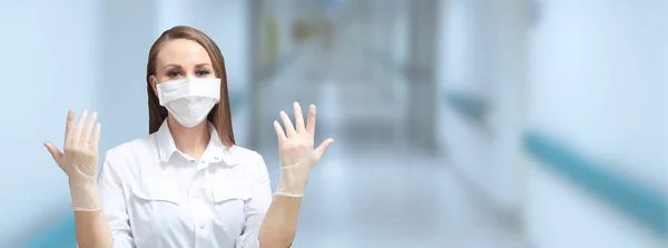 Tıbbi maskeli kadın doktor ve hastane koridorunun bulanık arka planında lateks koruyucu eldivenler. Salgın virüsü COVID-19