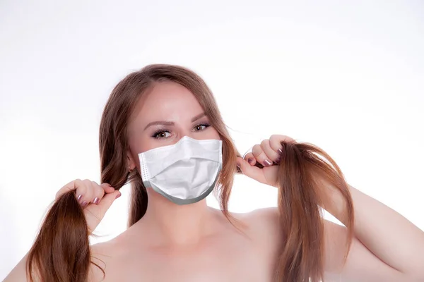 Cheerful young woman in a medical mask holding bunches of hair. The concept of health and beauty of hair.