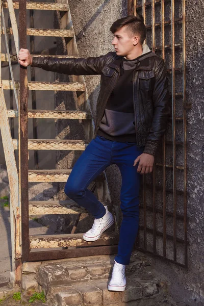 壁の近くの革ジャケット スタンディングでスタイリッシュな若いブルネット — ストック写真