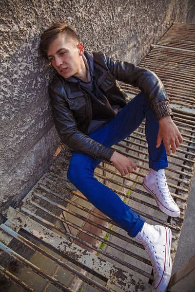 şık genç brunet duvara yakın oturan deri ceketli