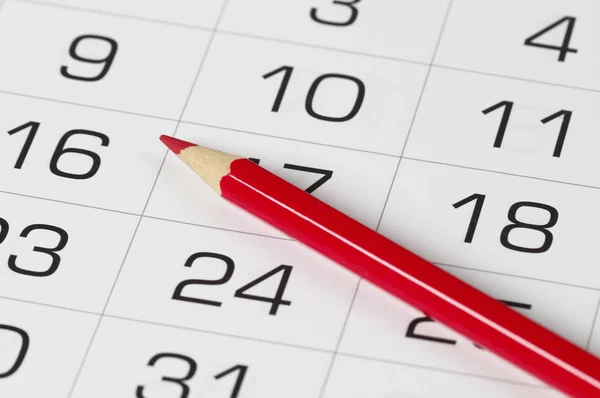 Красный карандаш над календарем — стоковое фото