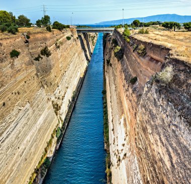 The Corinth Canal  is a canal that connects the Gulf of Corinth with the Saronic Gulf in the Aegean Sea. It cuts through the narrow Isthmus of Corinth and separates the Peloponnese from the Greek mainland, arguably making the peninsula an island.