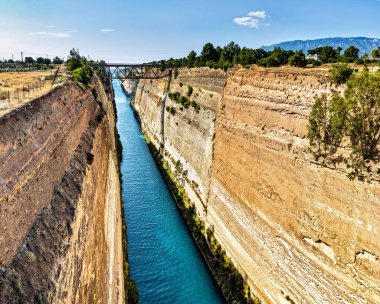 The Corinth Canal  is a canal that connects the Gulf of Corinth with the Saronic Gulf in the Aegean Sea. It cuts through the narrow Isthmus of Corinth and separates the Peloponnese from the Greek mainland, arguably making the peninsula an island.