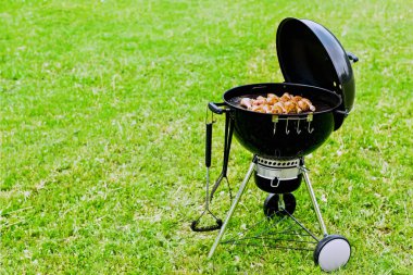 Barbekü, ızgara, çimenlerin üzerinde yuvarlak ayaklar, doğada bir yaz günü et kızartma..