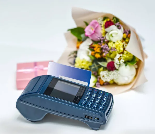 Modern blue payment terminal and card. The process of payment of the gift, bouquet.
