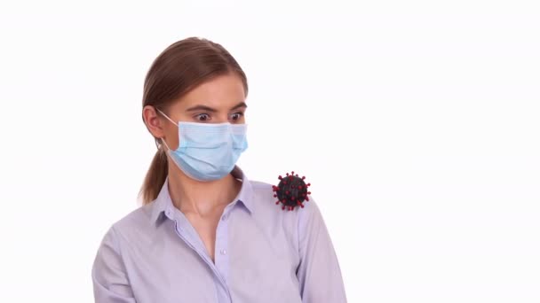 Женщина в медицинской маске испугалась вирусной клетки COVID-19 — стоковое видео